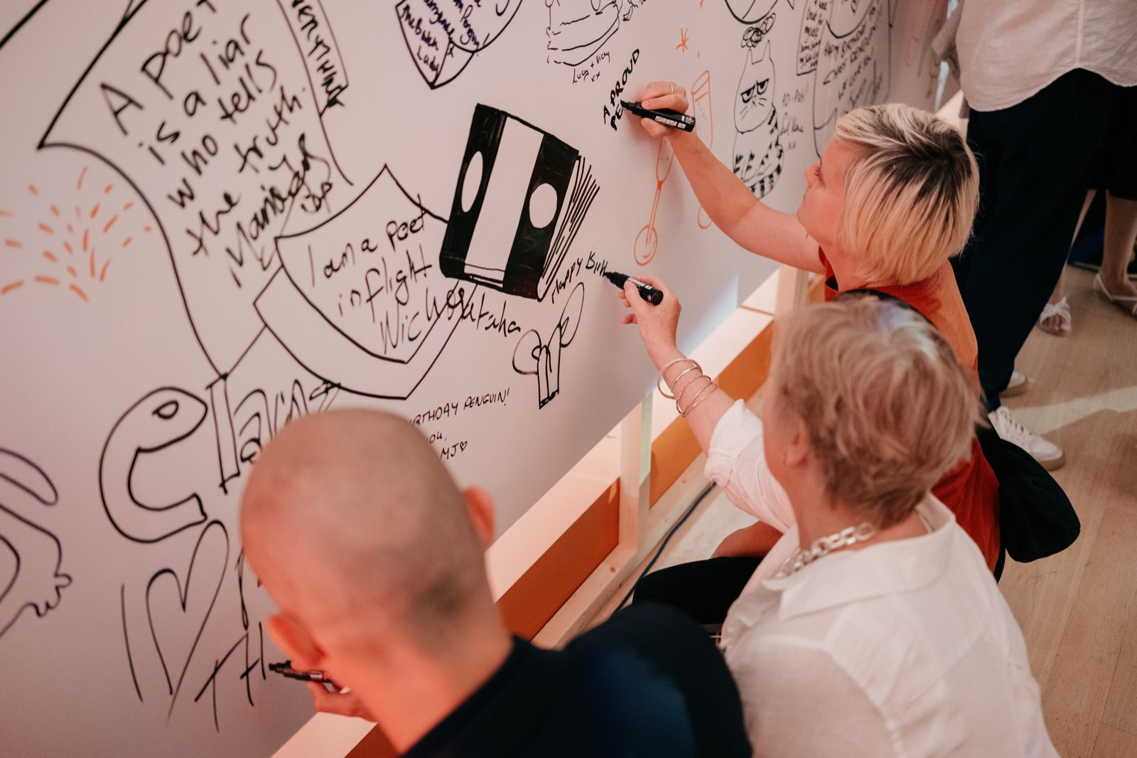 Guests writing and drawing on an interactive poetry wall at the Penguin 90th party