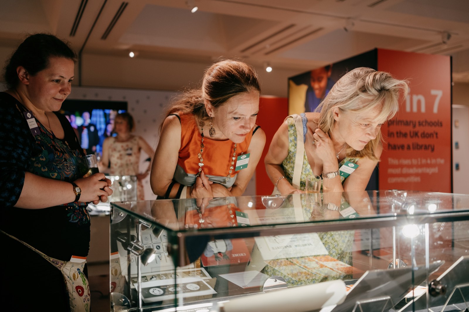 Visitors looking into a display case of Penguin archive material beside a literacy campaign panel
