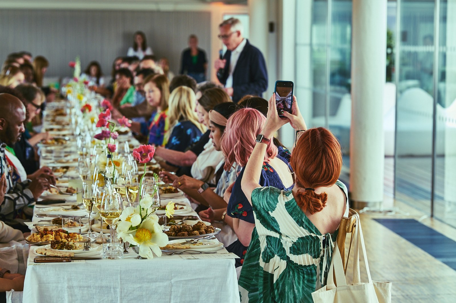 Guests along a long, flower-dressed table at a Penguin Presents dinner