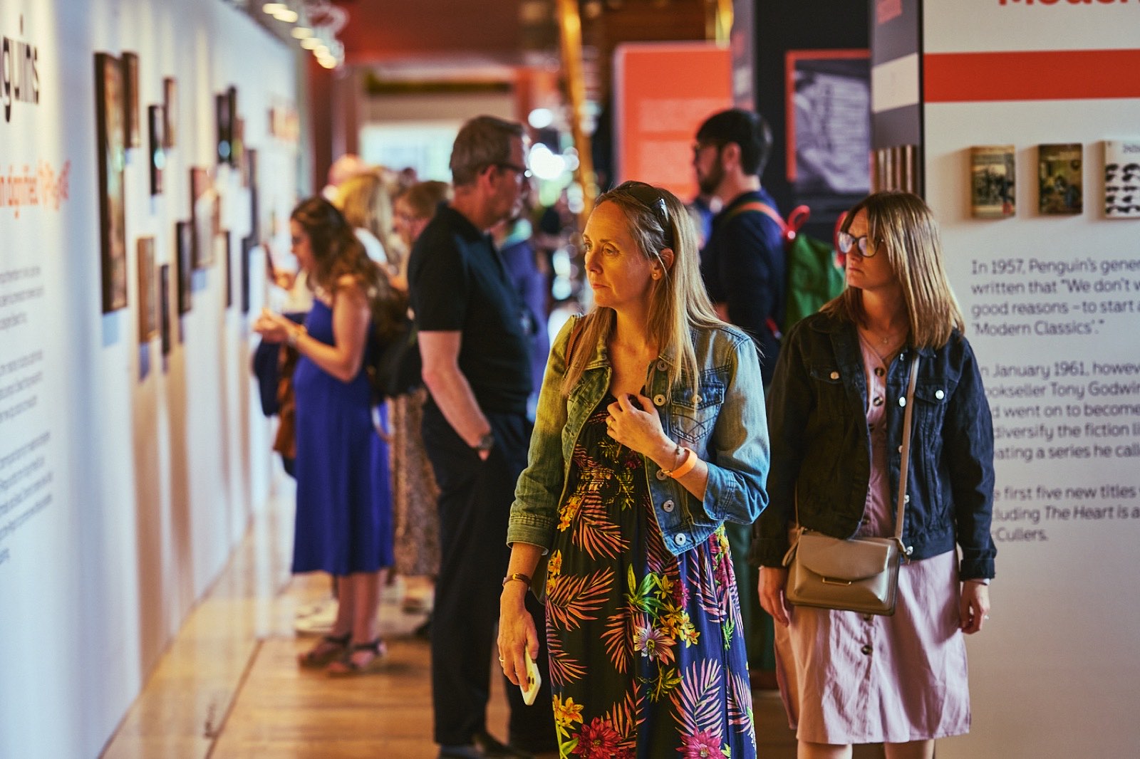 Visitors walking through an exhibition of Penguin book covers and archive material